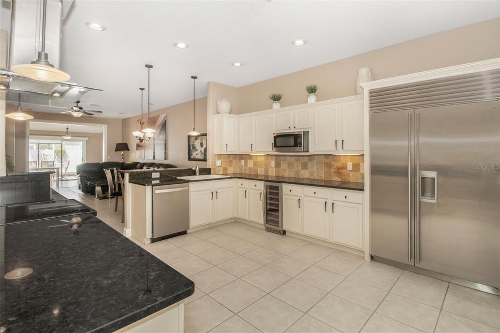 19331 Haskell Place Land O Lakes, FL 34638 - Photo 8 of 34 a kitchen with stainless steel appliances kitchen island granite countertop a stove a sink and a refrigerator