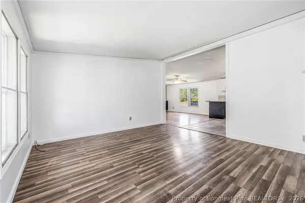 a view of an empty room with wooden floor and a window