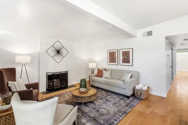 a living room with furniture a rug and kitchen view