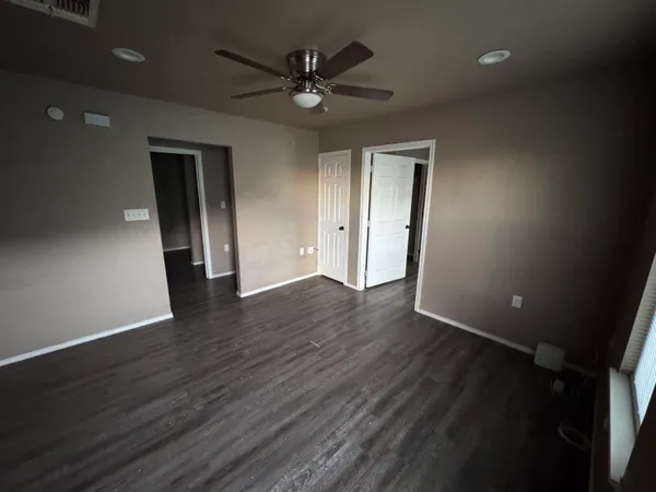 an empty room with wooden floor and a ceiling fan
