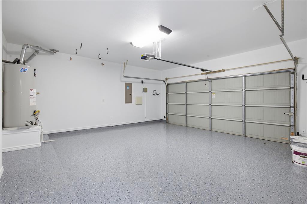 10001 Thurman Road Fort Worth, TX 76244 - Photo 32 of 40 Spacious garage featuring a light gray flake epoxy floor, white painted walls, a panel garage door, and overhead lighting