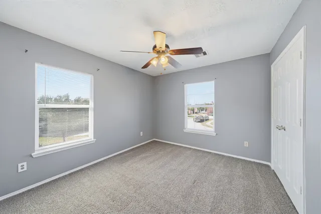 a view of an empty room with window and chandelier fan