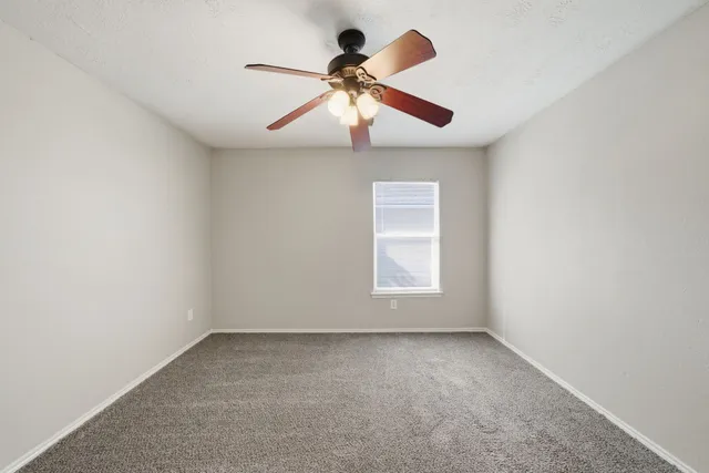 an empty room with a ceiling fan and window