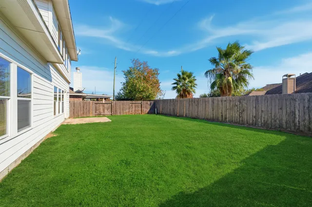 a view of a backyard with grass and a fence