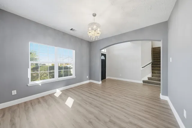 a view of an empty room with wooden floor and a window