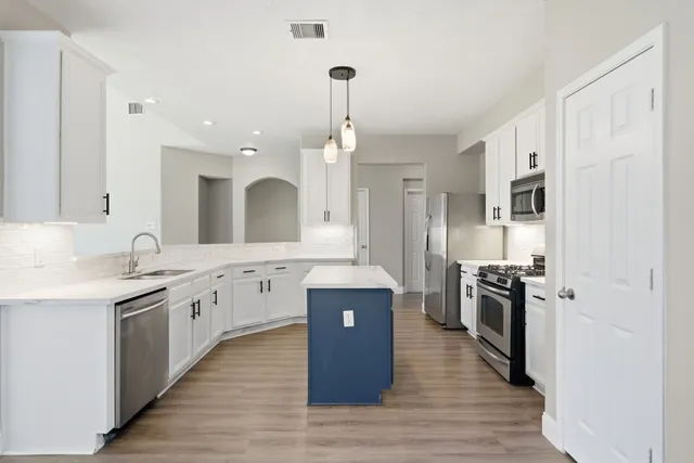a large kitchen with stainless steel appliances granite countertop a lot of counter space and wooden floor