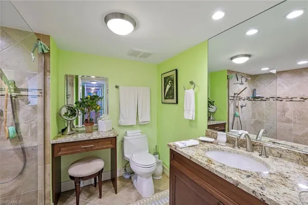 a bathroom with a granite countertop sink a toilet a mirror and shower