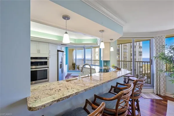 a dining hall with stainless steel appliances granite countertop a stove and a kitchen view
