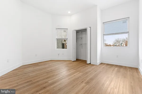 an empty room with wooden floor and windows