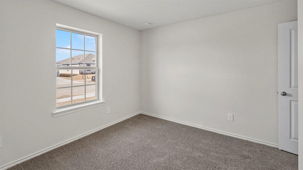 1969 Freeman Street Tyler, TX 75704 - Photo 20 of 30 Bright room featuring a grid-pattern window, neutral wall paint, gray carpet flooring, white baseboards, and a white interior door
