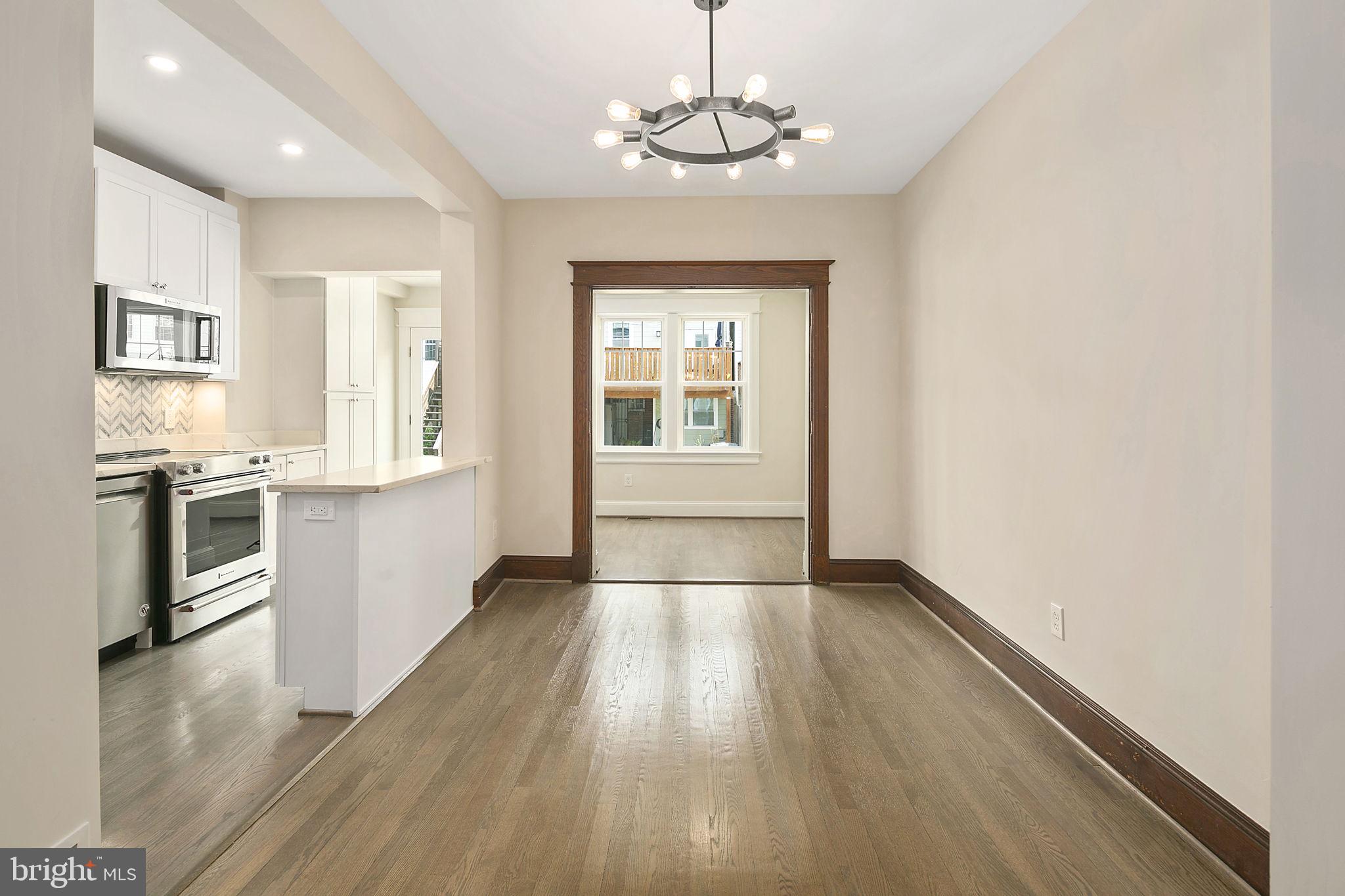 1242 Oates Street Northeast Washington, DC 20002 - Photo 15 of 47 an empty room with wooden floor kitchen view and a window