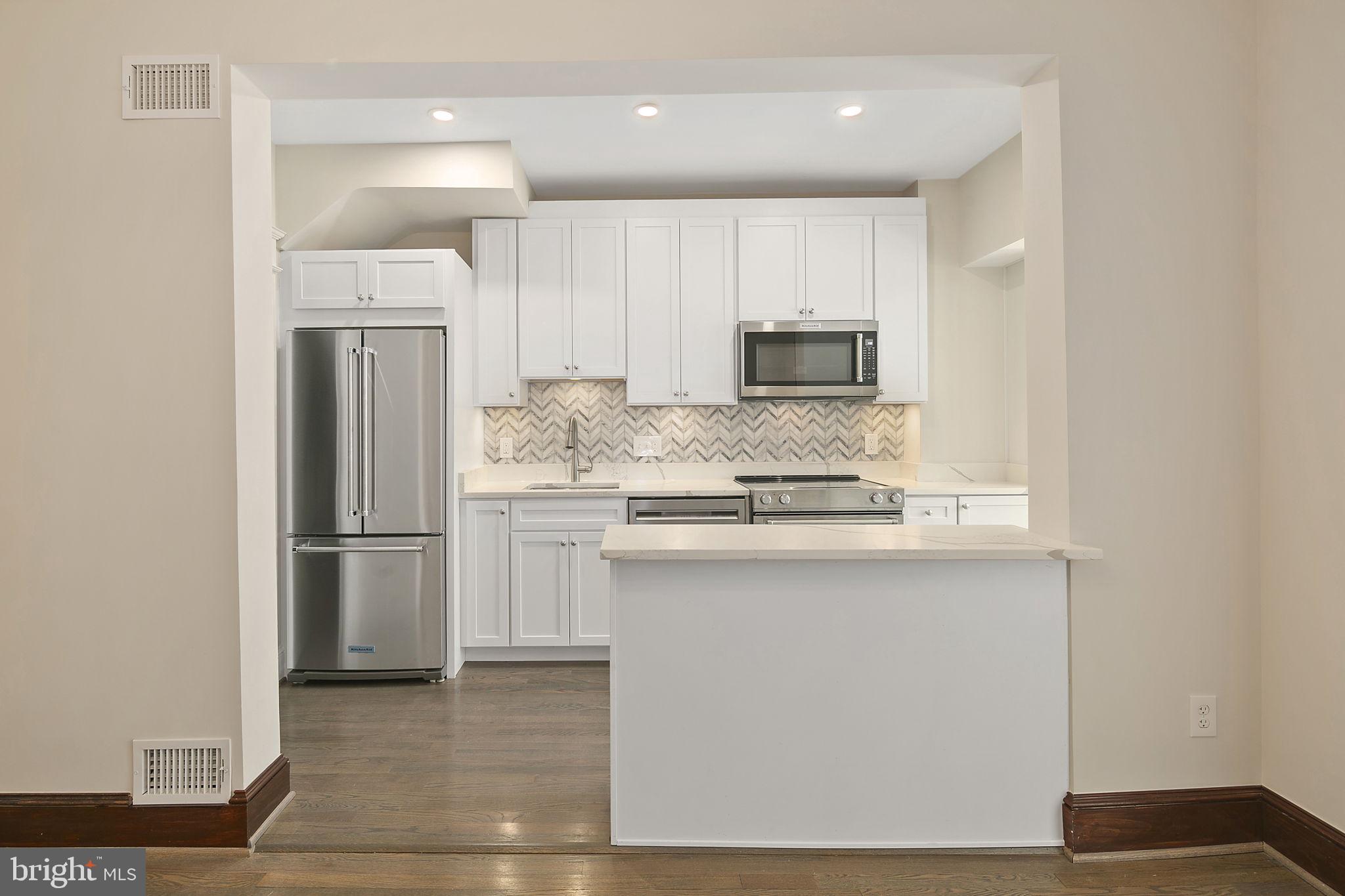 1242 Oates Street Northeast Washington, DC 20002 - Photo 20 of 47 a kitchen with kitchen island white cabinets and refrigerator