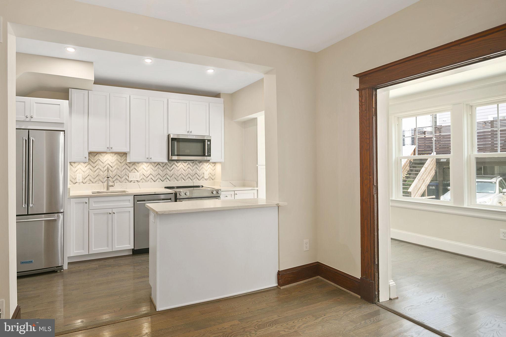 1242 Oates Street Northeast Washington, DC 20002 - Photo 21 of 47 a kitchen with kitchen island granite countertop white cabinets and refrigerator