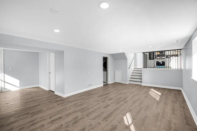 a view of an empty room with wooden floor and kitchen
