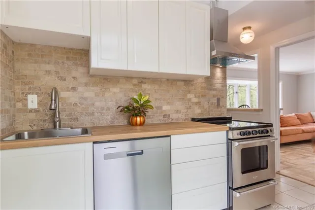 a kitchen with stainless steel appliances granite countertop a sink a stove and white cabinets