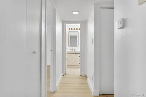 a view of a hallway with wooden floor and a bathroom