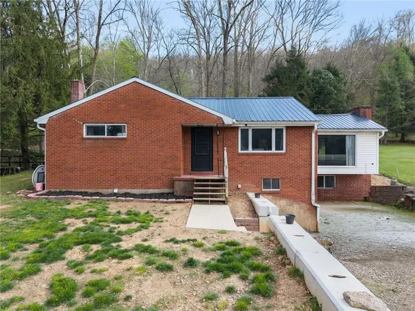 a front view of house with yard and trees in the background