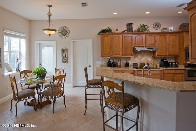 3385 Kings Road South St. Augustine, FL 32086 - Photo 12 of 36 a kitchen with granite countertop a table chairs stove a sink and dishwasher