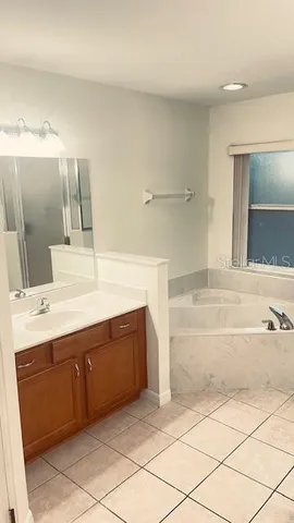 a spacious bathroom with a tub sink and mirror