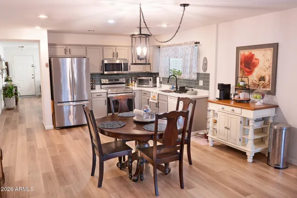 a kitchen with stainless steel appliances a dining table chairs stove and refrigerator