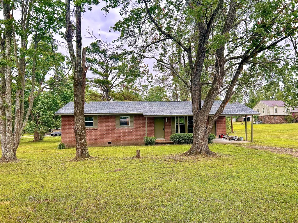 a front view of a house with a garden and trees