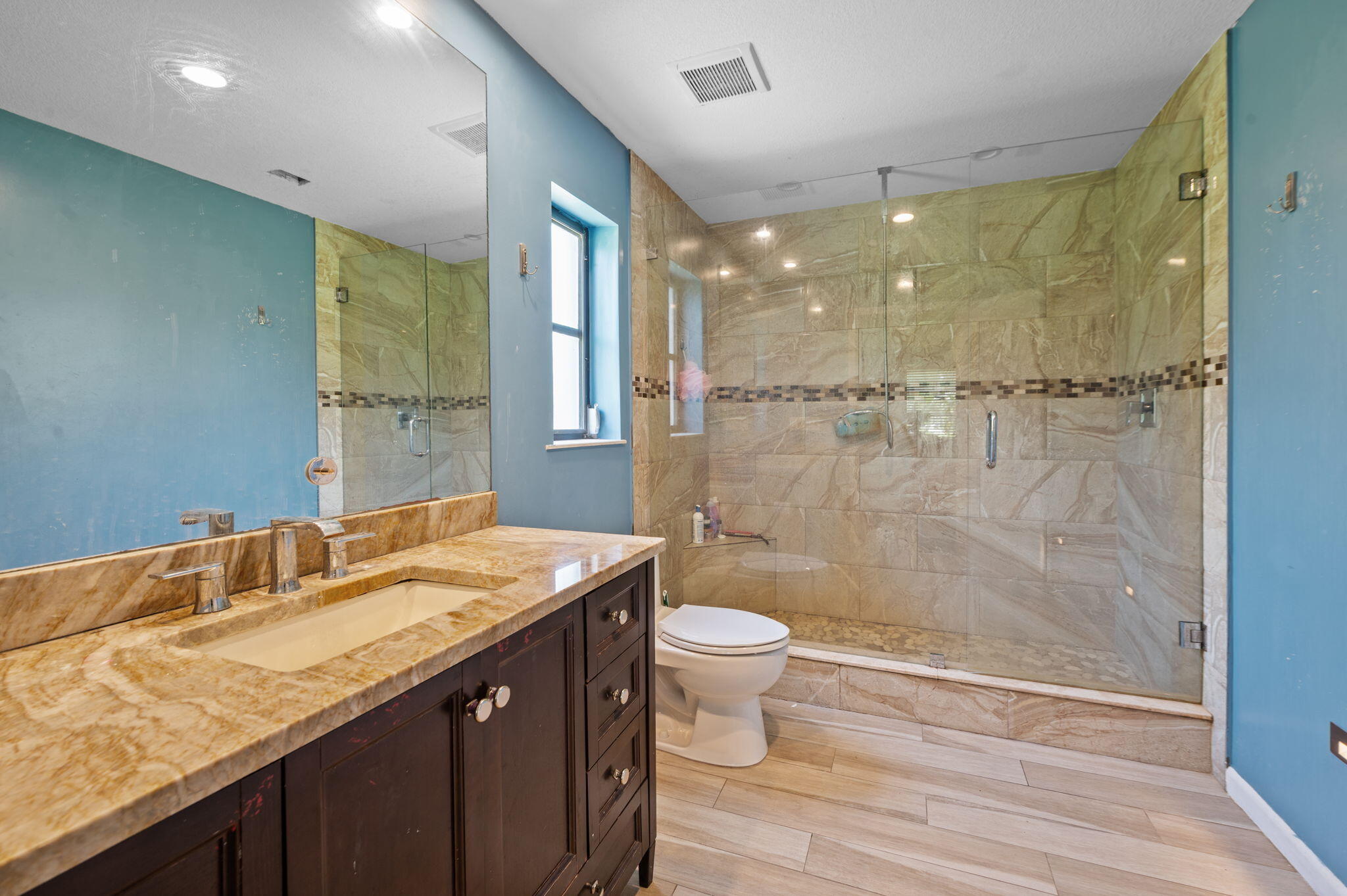 2587 E Road Loxahatchee Groves, FL 33470 - Photo 13 of 46 a bathroom with a granite countertop sink a toilet a mirror and shower