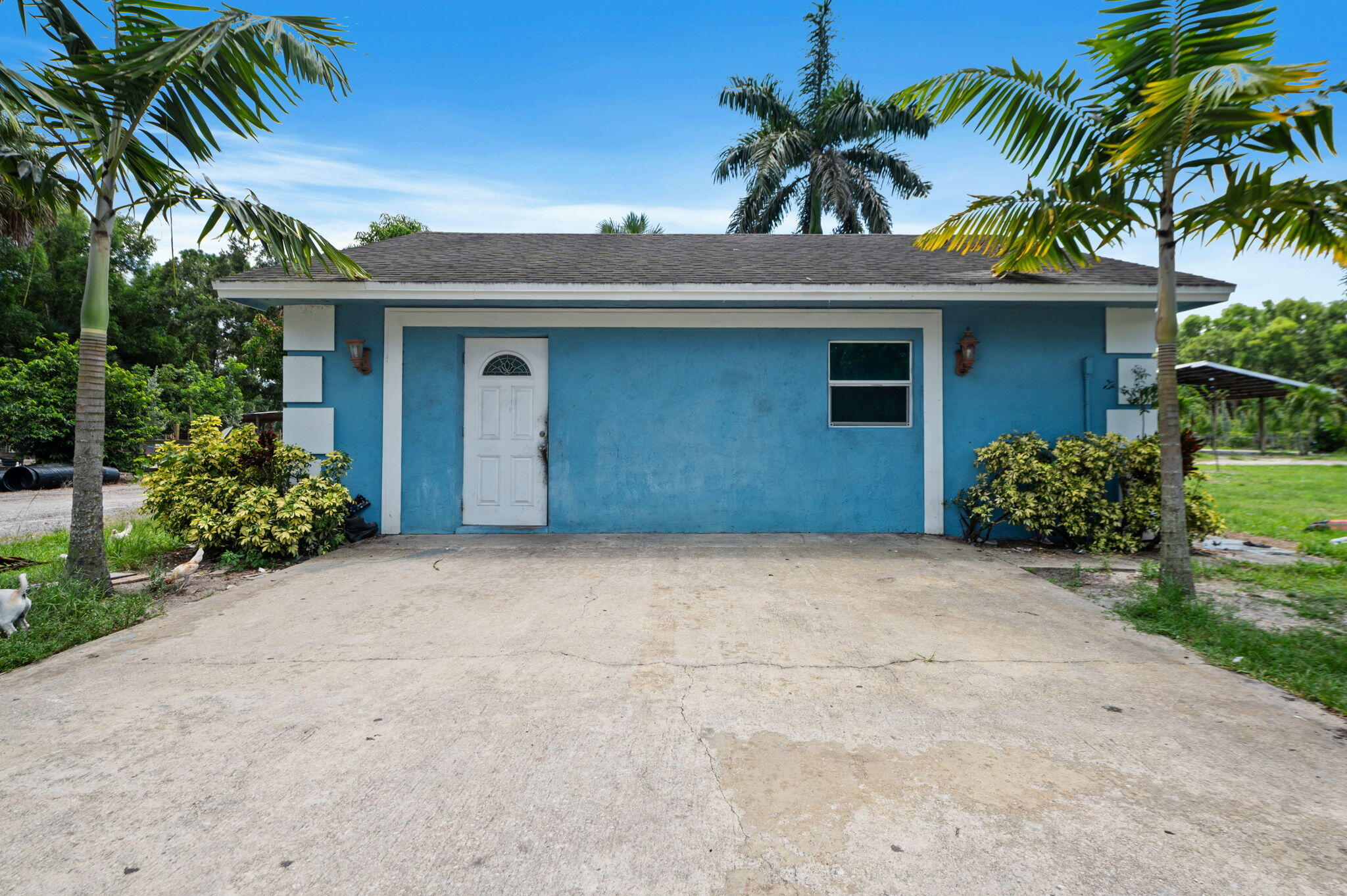 2587 E Road Loxahatchee Groves, FL 33470 - Photo 25 of 46 a view of a house with a yard and a garage
