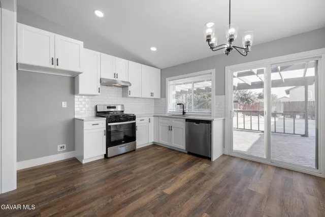 a kitchen with granite countertop wooden floors stainless steel appliances and white cabinets
