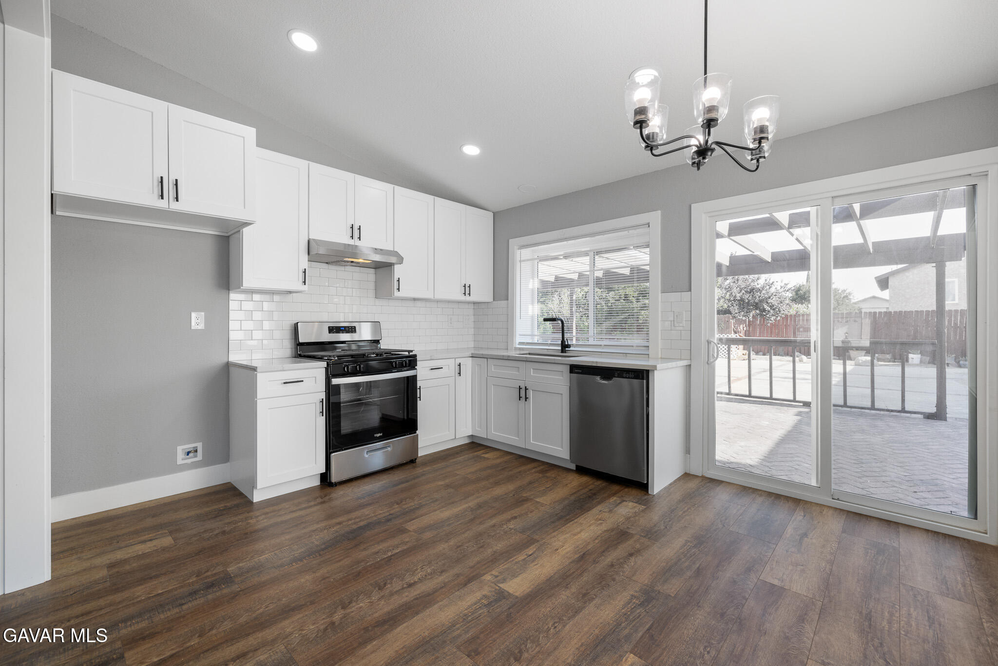 4753 East Ave R 11 Palmdale, CA 93552 - Photo 12 of 41 a kitchen with granite countertop wooden floors stainless steel appliances and white cabinets