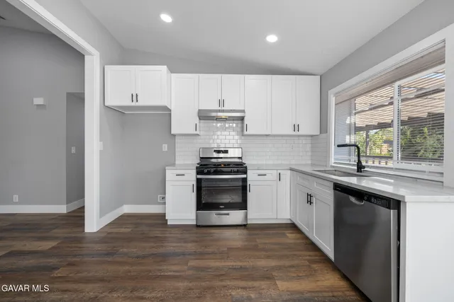 a kitchen with granite countertop white cabinets and appliances