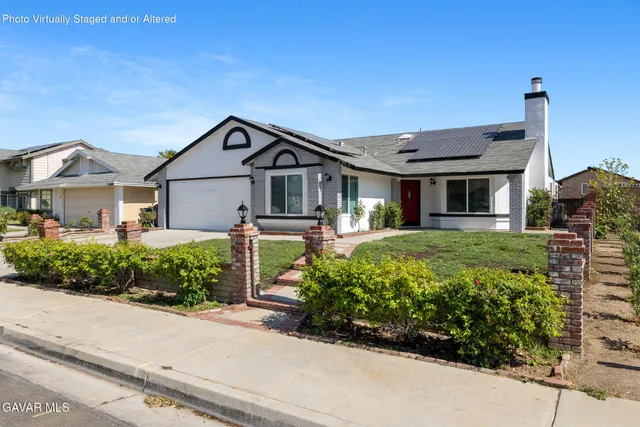 a front view of a house with a yard and potted plants