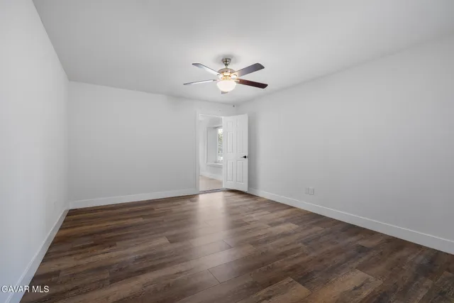 a view of an empty room with a ceiling fan and wooden floor