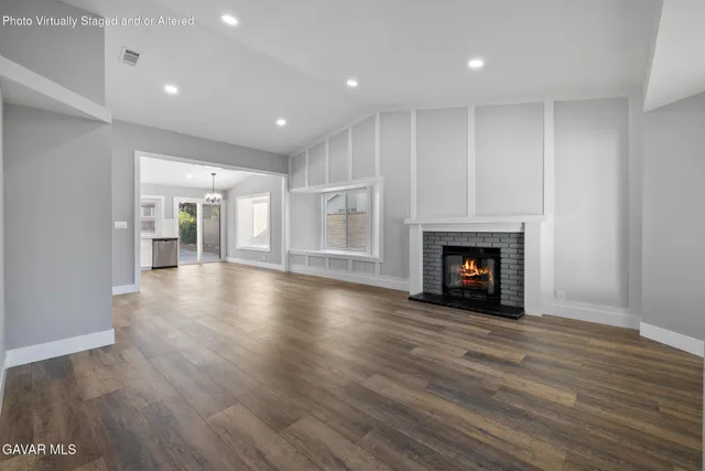 a view of an empty room with wooden floor fireplace and a window