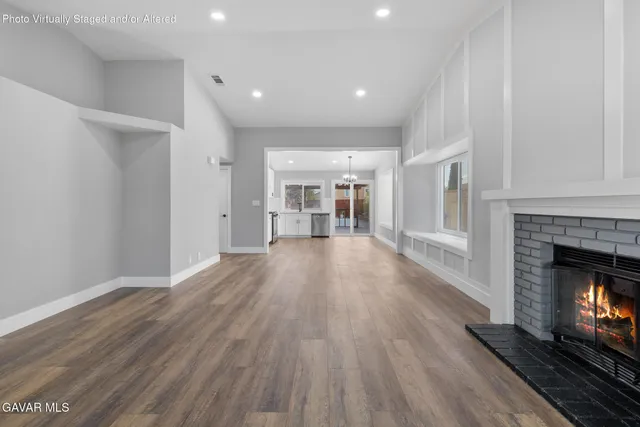 a view of a room with wooden floor fire place and windows