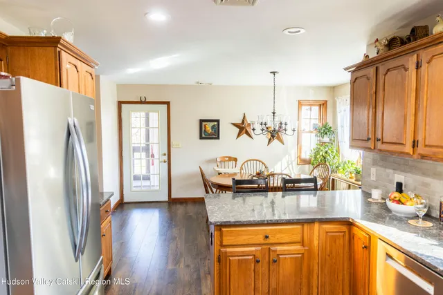 a kitchen with stainless steel appliances granite countertop a refrigerator a sink dishwasher and wooden cabinets with wooden floor