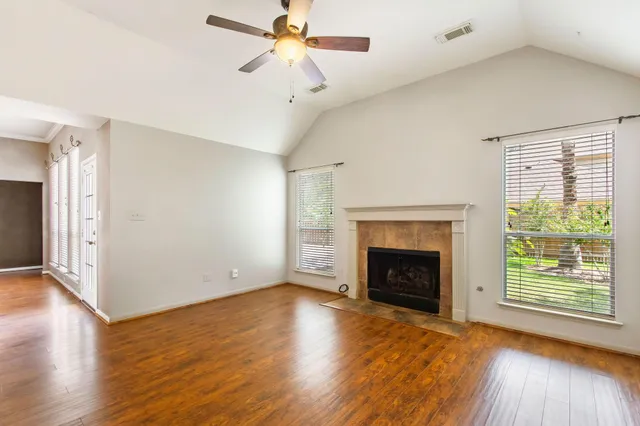a view of an empty room with wooden floor fireplace and a window