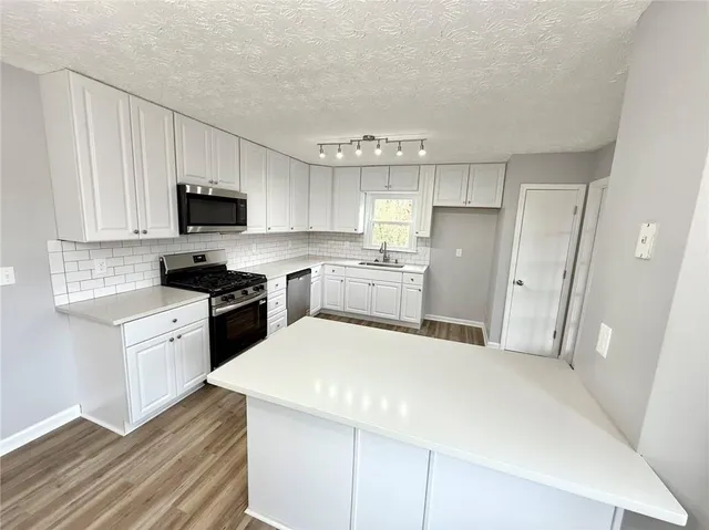a kitchen with a sink a refrigerator a stove top oven and white cabinets