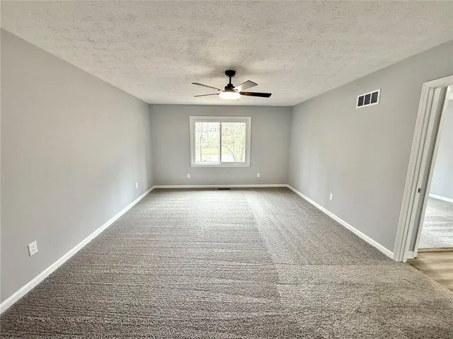 an empty room with windows and ceiling fan