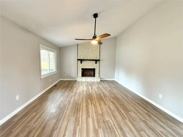 a view of empty room with wooden floor fireplace and window