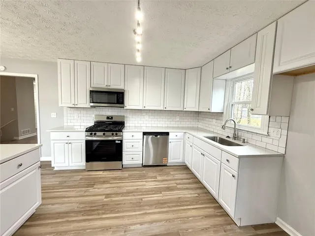 a kitchen with stainless steel appliances a sink stove top oven and cabinets
