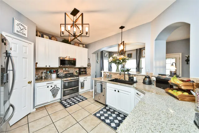 a kitchen with stainless steel appliances a stove a sink dishwasher a refrigerator oven and white cabinets next to a window