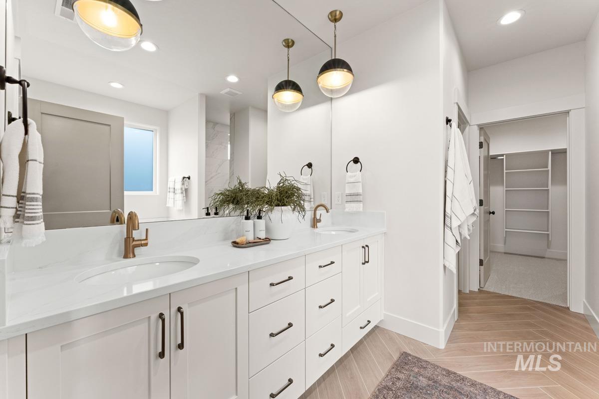 13338 North Spring Creek Way Boise, ID 83714 - Photo 19 of 46 Double vanity featuring white shaker cabinetry, brass hardware, and a light-toned countertop with integrated sinks