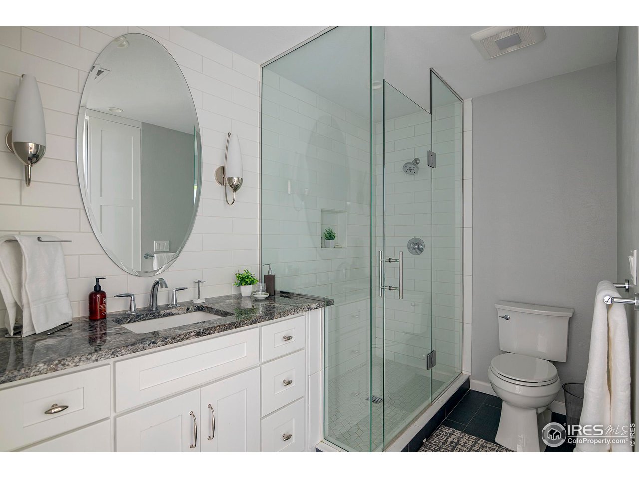 7034 Indian Peaks Trail Boulder, CO 80301 - Photo 32 of 40 a bathroom with a granite countertop sink toilet a mirror a vanity and shower