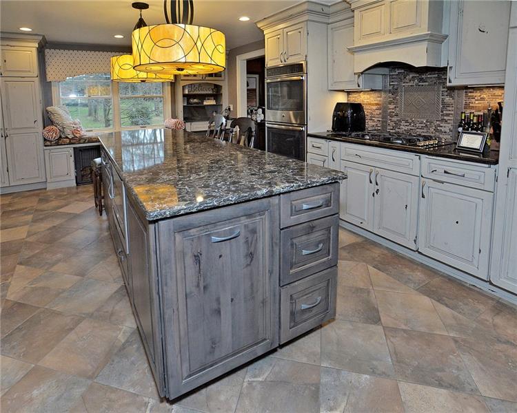 111 McDermott Road Trafford, PA 15085 - Photo 3 of 25 Wow! In 2017 a complete high-end overhaul of the kitchen was completed. The 10 foot island is the centerpiece of this amazing area! Gorgeous Quartz countertops are on both the island and surrounding counters. The island features outlets with USB ports & internal power in cabinets for ancillary appliances (a hidden swing-out locking shelf for a mixer), pull-out cutting board, built-in under counter microwave, and room for seating! Great window bench seat & built-in desk area too!