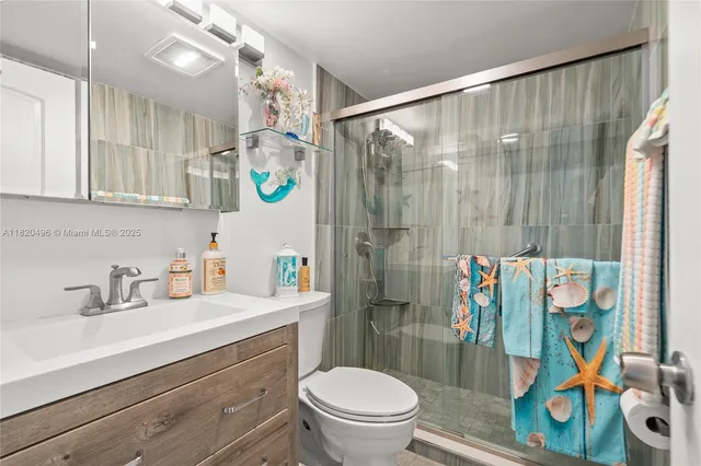 a bathroom with a sink a toilet a mirror a vanity and shower