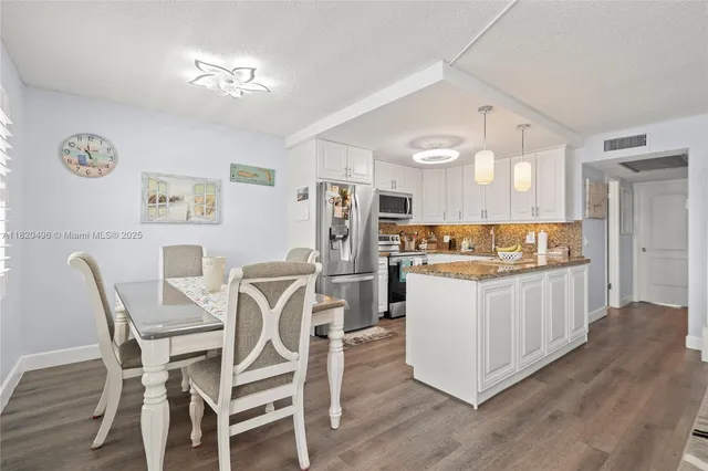 a kitchen with a dining table chairs cabinets and stainless steel appliances