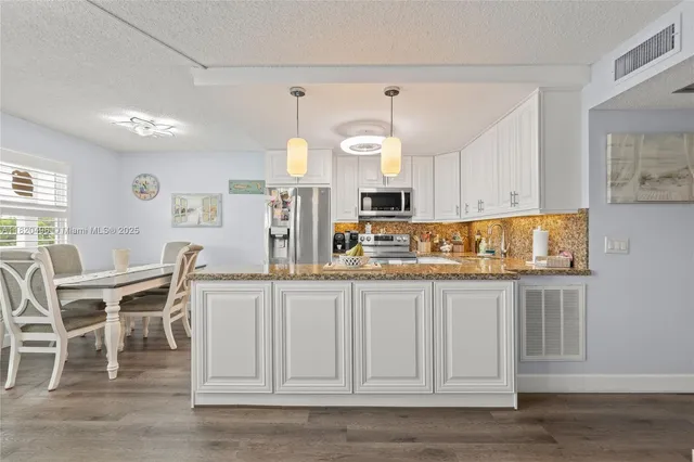 a kitchen with stainless steel appliances granite countertop a white cabinets and stove top oven