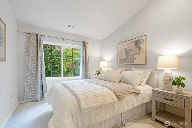 a bedroom with a bed and a lamp on dresser