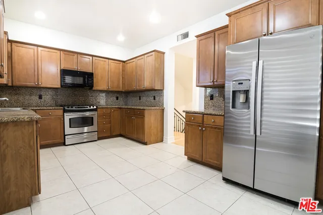 a kitchen with stainless steel appliances granite countertop a refrigerator and a stove top oven
