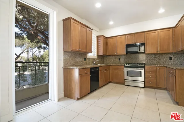 a kitchen with stainless steel appliances granite countertop a stove a sink and a refrigerator